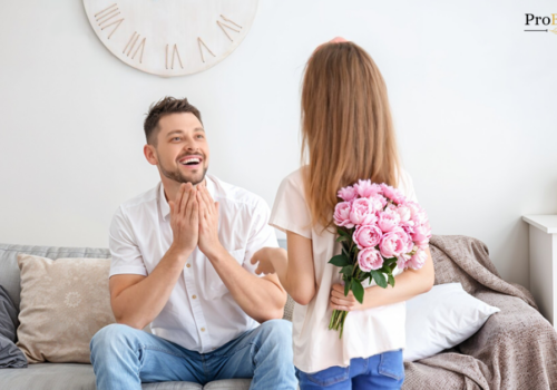 Little girl surprising her dad with a bouquet of pink fathers day flowers at home